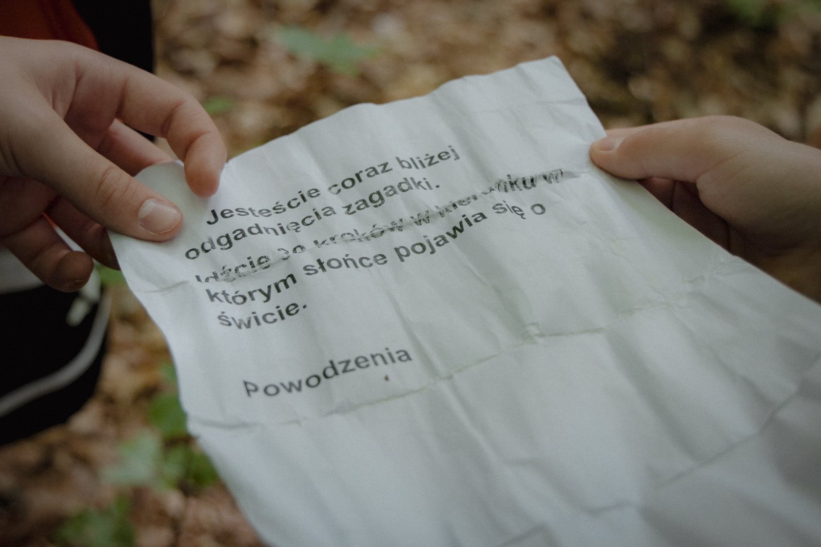 Uczestnicy czytają zadanie z kartki znalezionej na trasie